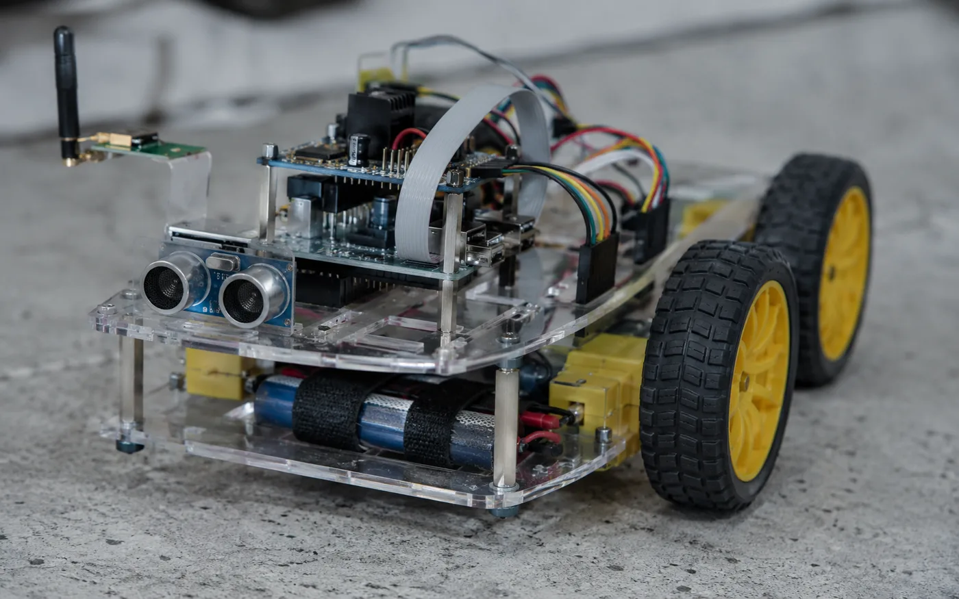 Four-wheeled robotics vehicle with stacked microcontroller boards, motor driver and an ultrasonic sensor